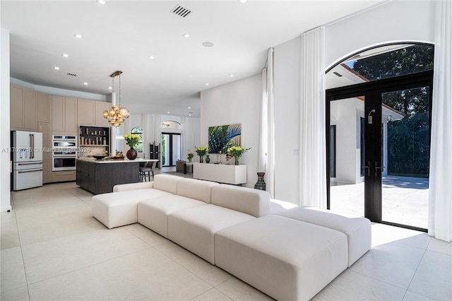 tiled living room with a chandelier and french doors