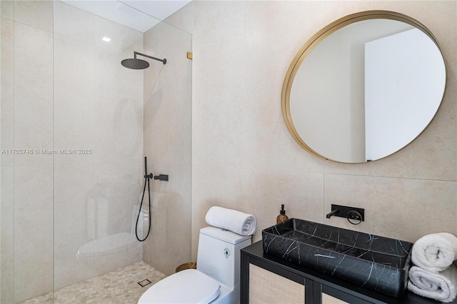 bathroom featuring tile walls, toilet, tiled shower, and vanity