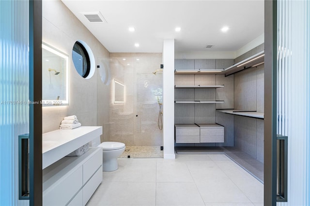 bathroom featuring tile patterned floors, vanity, tile walls, toilet, and a shower with shower door