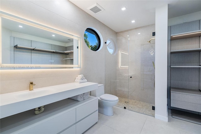 bathroom with an enclosed shower, tile patterned flooring, vanity, tile walls, and toilet