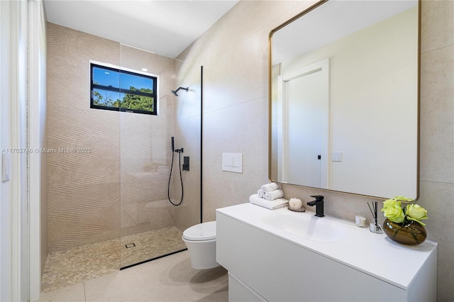 bathroom featuring vanity, a tile shower, tile patterned floors, and toilet