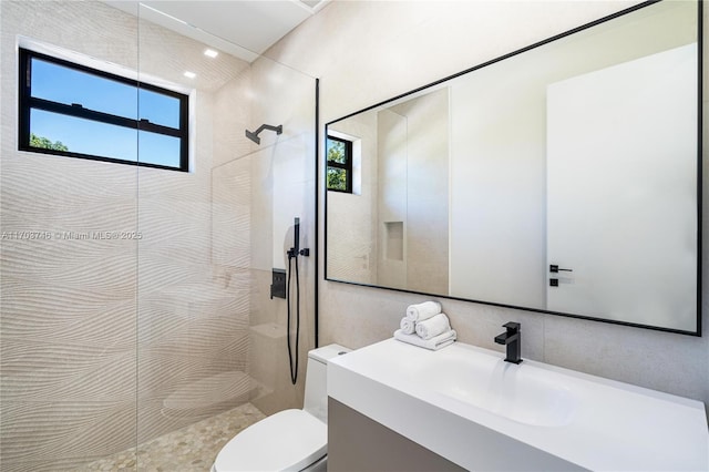 bathroom featuring toilet, a tile shower, and vanity