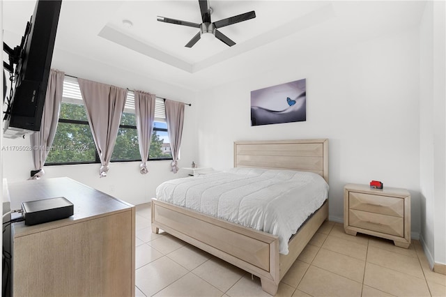 bedroom featuring light tile patterned floors, a tray ceiling, and ceiling fan