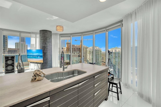 kitchen featuring a wealth of natural light, sink, light tile patterned floors, and a wall of windows