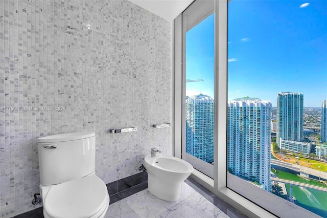 bathroom with a bidet, tile walls, and toilet