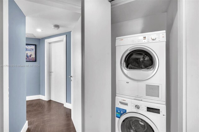 clothes washing area with dark parquet flooring and stacked washer / dryer