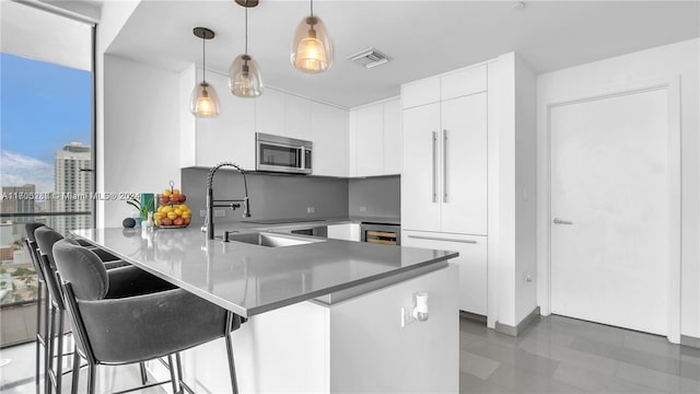 kitchen featuring white cabinetry, sink, hanging light fixtures, kitchen peninsula, and a breakfast bar