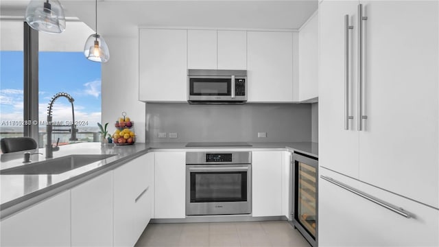 kitchen with appliances with stainless steel finishes, sink, pendant lighting, white cabinets, and wine cooler