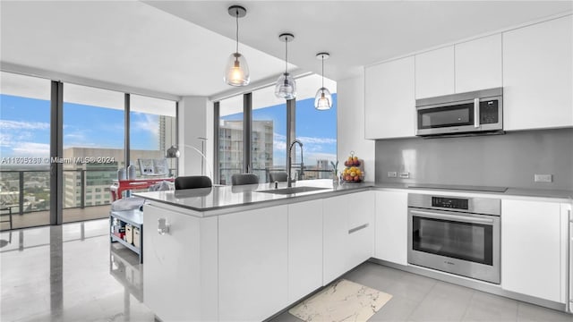 kitchen featuring sink, white cabinets, decorative light fixtures, and appliances with stainless steel finishes