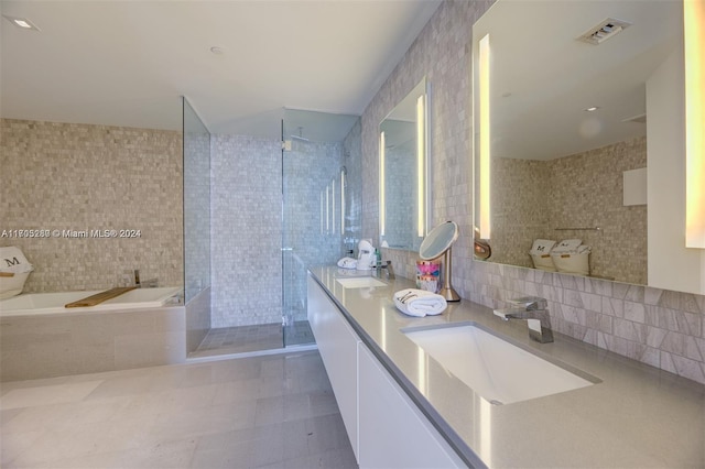 bathroom featuring vanity, tasteful backsplash, tile walls, and independent shower and bath