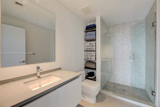 bathroom featuring tile patterned flooring, vanity, toilet, and an enclosed shower