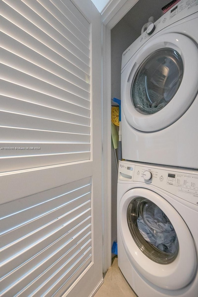 laundry room with light tile patterned floors and stacked washing maching and dryer