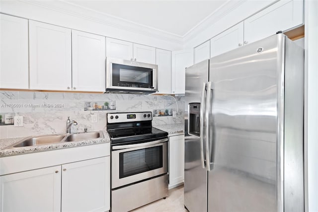 kitchen with light stone countertops, appliances with stainless steel finishes, ornamental molding, sink, and white cabinets