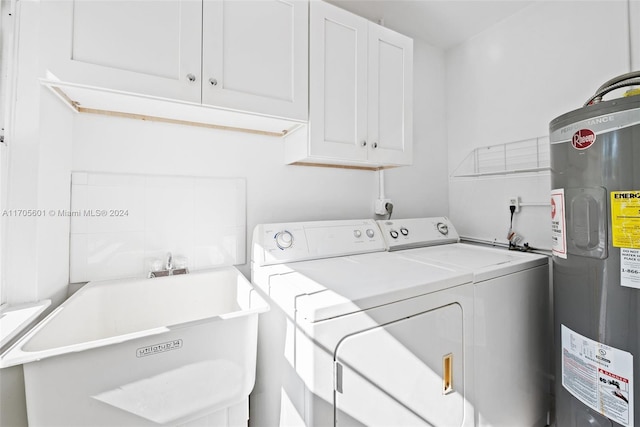 clothes washing area featuring washer and dryer, cabinets, sink, and water heater