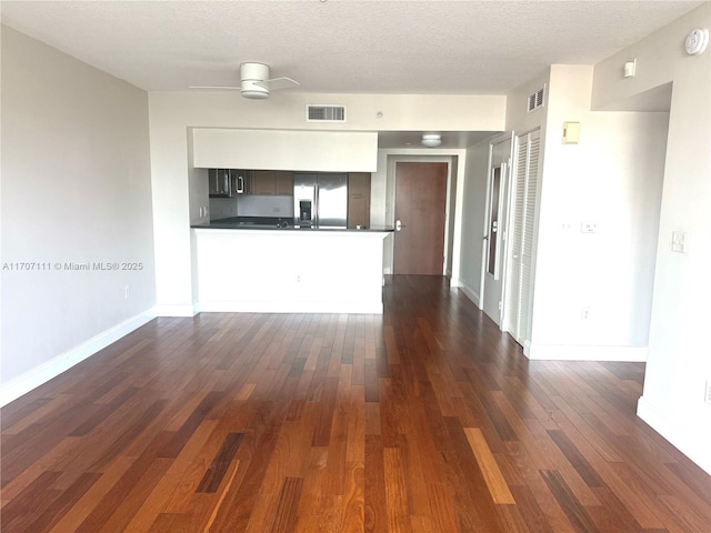 unfurnished living room featuring dark hardwood / wood-style flooring, ceiling fan, and a textured ceiling