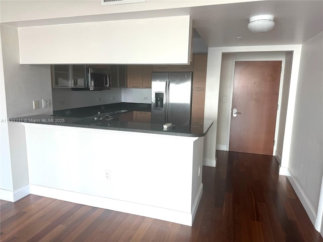 kitchen featuring dark wood-type flooring, kitchen peninsula, and appliances with stainless steel finishes