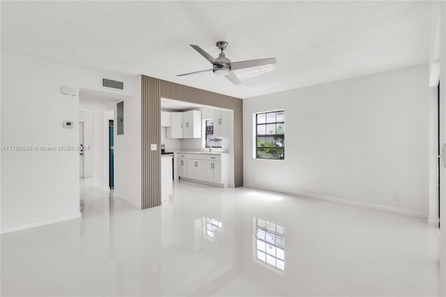 unfurnished living room featuring a textured ceiling, ceiling fan, and sink