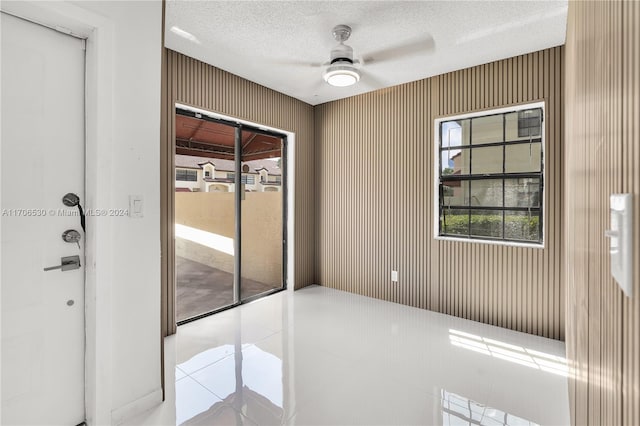 spare room with ceiling fan, light tile patterned floors, and a textured ceiling