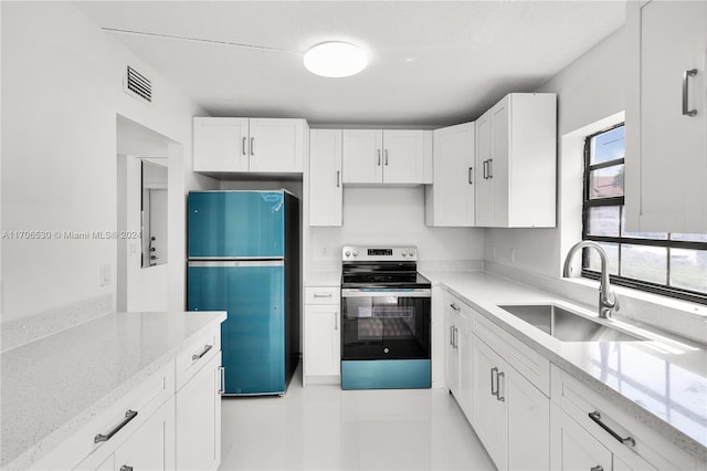 kitchen with refrigerator, light stone counters, sink, white cabinets, and stainless steel electric range