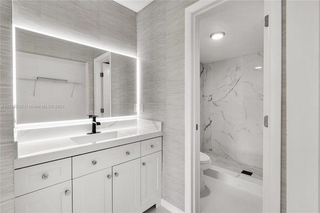 bathroom featuring toilet, vanity, and tiled shower