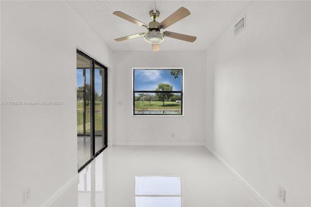 empty room with ceiling fan and a textured ceiling