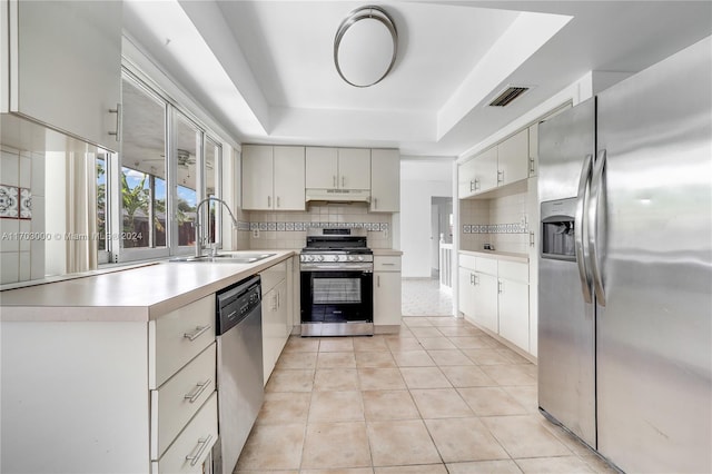 kitchen with a raised ceiling, sink, light tile patterned floors, and stainless steel appliances