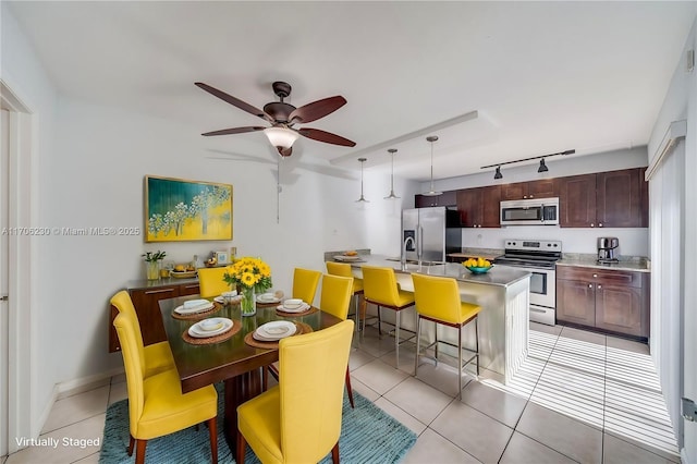 tiled dining space featuring sink, track lighting, and ceiling fan