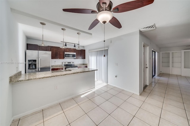 kitchen with sink, appliances with stainless steel finishes, light stone counters, dark brown cabinetry, and decorative light fixtures