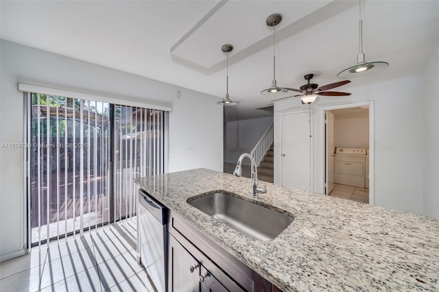 kitchen featuring sink, hanging light fixtures, light stone countertops, washer and dryer, and stainless steel dishwasher