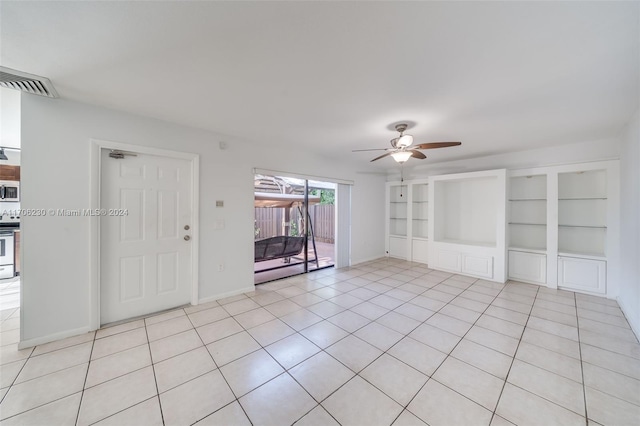 unfurnished living room with built in shelves, ceiling fan, and light tile patterned floors