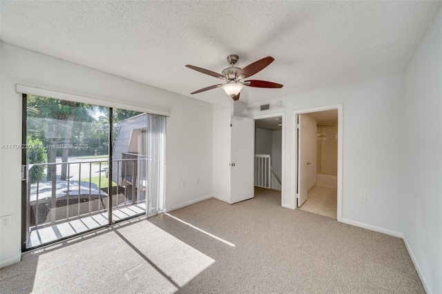 unfurnished bedroom featuring ensuite bath, light colored carpet, access to exterior, ceiling fan, and a textured ceiling