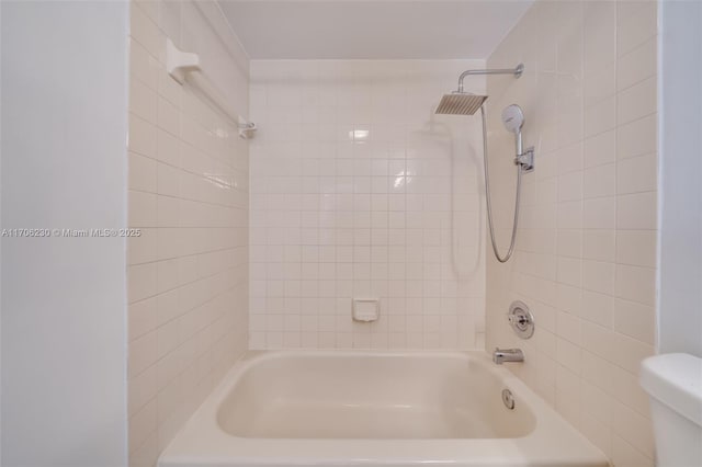 bathroom with toilet and tiled shower / bath