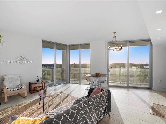 living room with light hardwood / wood-style floors, a wall of windows, and an inviting chandelier