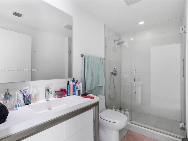 bathroom with tile patterned floors, vanity, toilet, and a shower with door