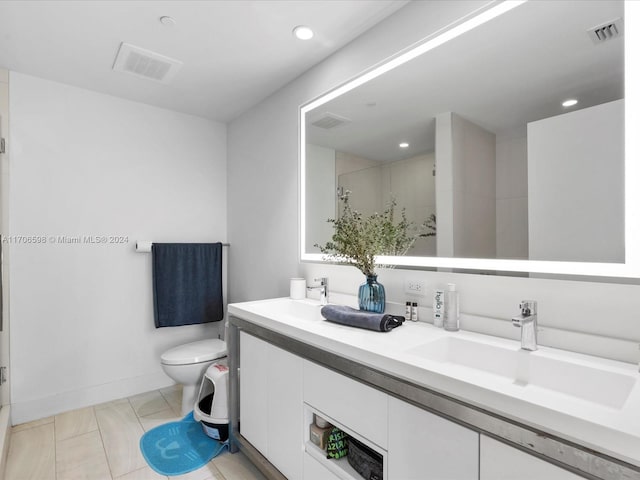 bathroom featuring tile patterned flooring, vanity, toilet, and a shower with shower door