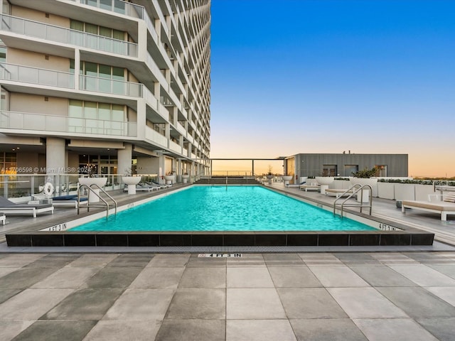 pool at dusk featuring a patio