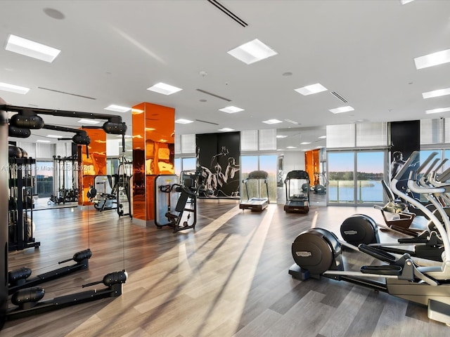 exercise room with hardwood / wood-style floors, floor to ceiling windows, and a water view