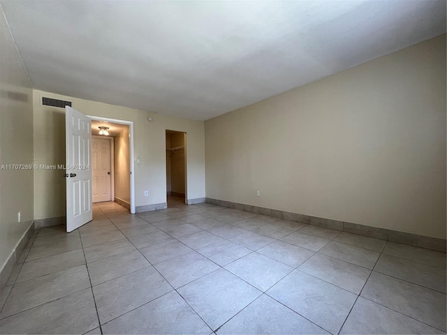 unfurnished bedroom with light tile patterned flooring, a spacious closet, and a closet