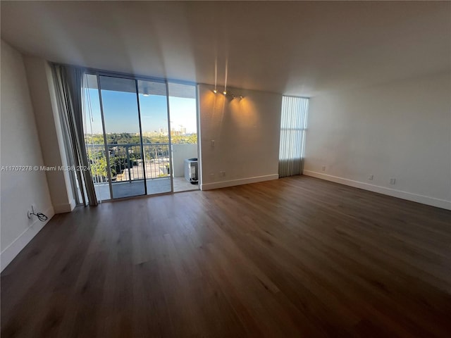 empty room featuring floor to ceiling windows and dark hardwood / wood-style flooring