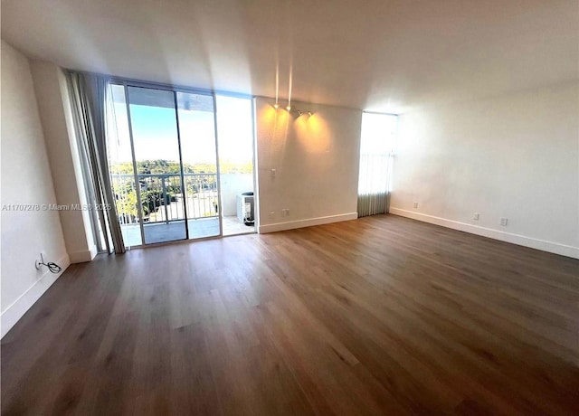empty room featuring baseboards, floor to ceiling windows, and dark wood-style flooring