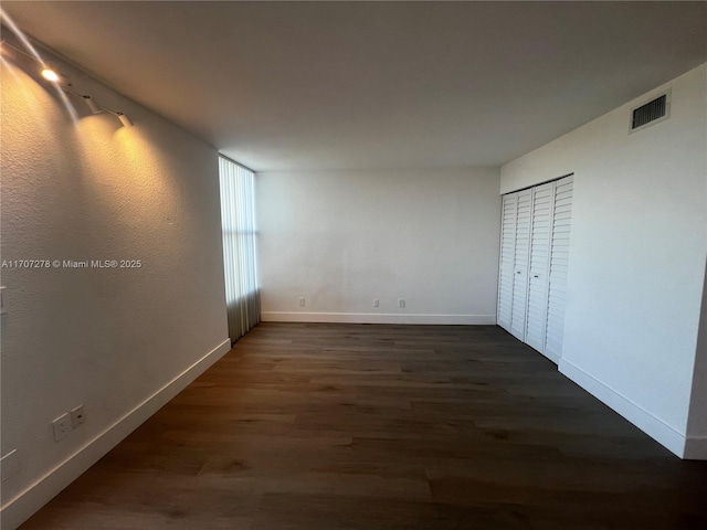 interior space featuring baseboards, dark wood-type flooring, and visible vents