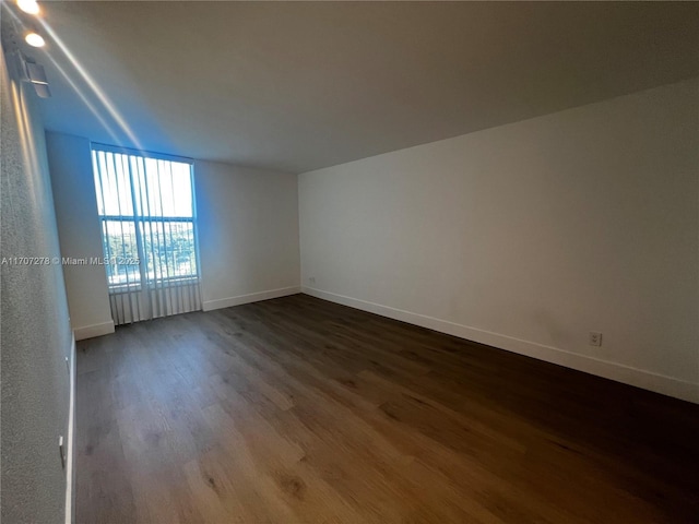 unfurnished room featuring baseboards and wood finished floors