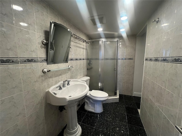 bathroom with toilet, a shower with shower door, and tile walls