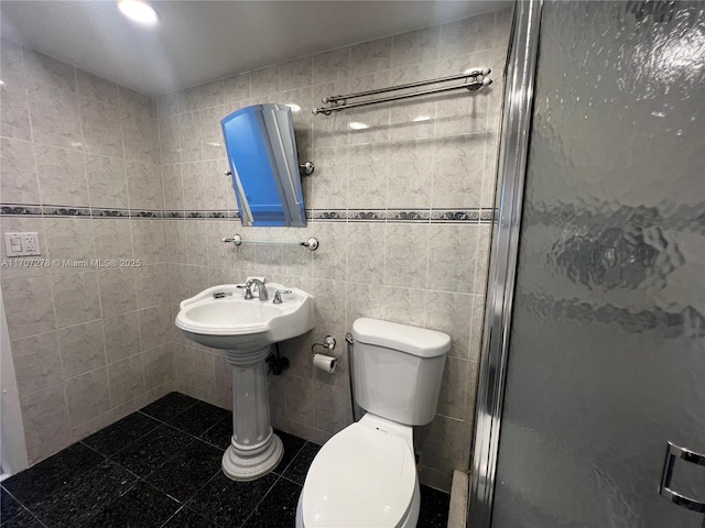 bathroom featuring toilet, tile walls, and a stall shower
