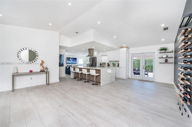 living room featuring vaulted ceiling, light hardwood / wood-style flooring, and french doors