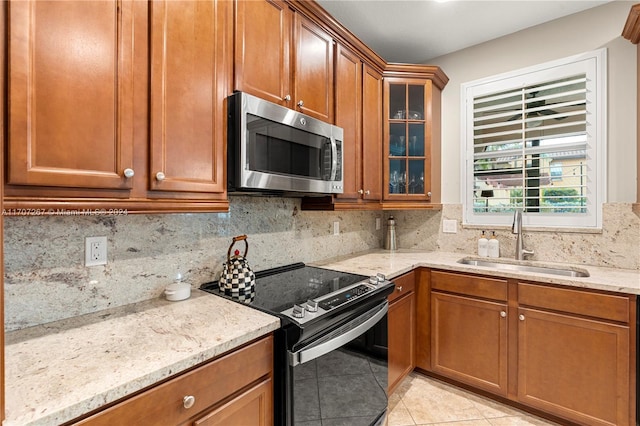 kitchen featuring tasteful backsplash, light stone counters, black range with electric cooktop, sink, and light tile patterned flooring