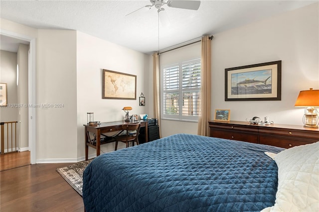 bedroom with ceiling fan, dark wood-type flooring, and a textured ceiling