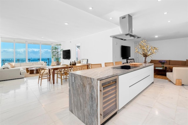 kitchen featuring island range hood, black electric cooktop, beverage cooler, white cabinets, and a center island