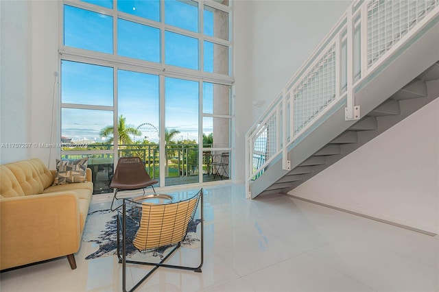 living room with tile patterned floors, plenty of natural light, and a towering ceiling