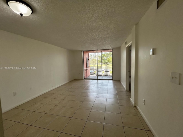 tiled empty room featuring a textured ceiling